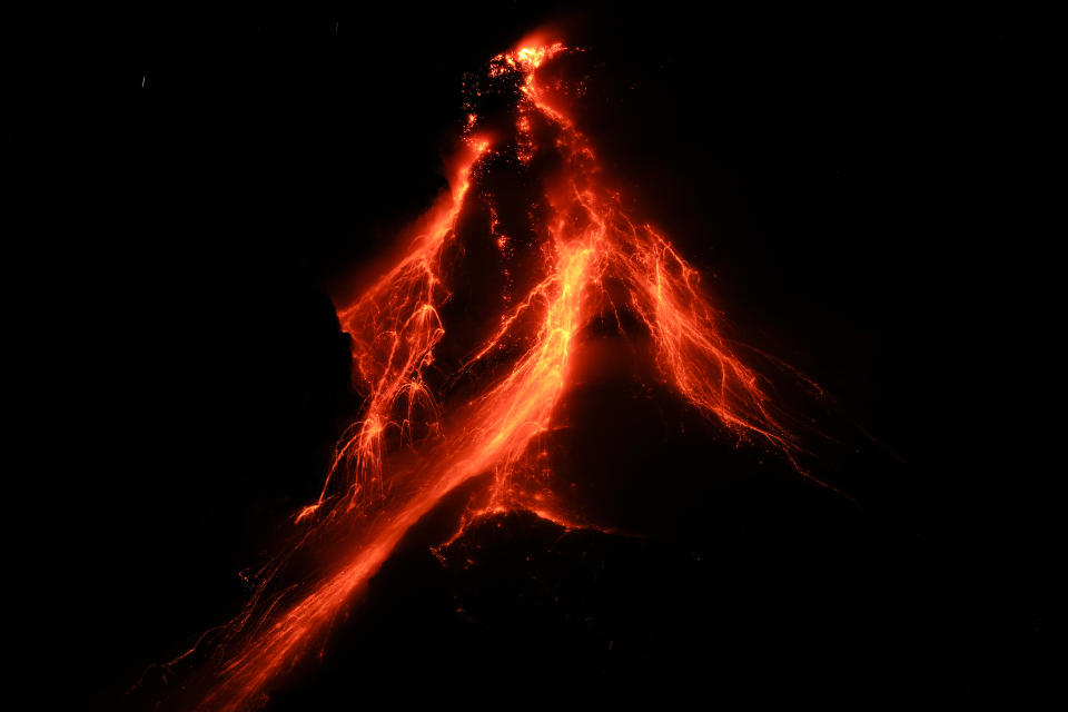 Lava flows down the slopes of Mayon volcano as seen from Daraga town, Albay province, northeastern Philippines, Tuesday, June 13, 2023. Truckloads of villagers on Tuesday fled from Philippine communities close to gently erupting Mayon volcano, traumatized by the sight of red-hot lava flowing down its crater and sporadic blasts of ash. (AP Photo/Aaron Favila)