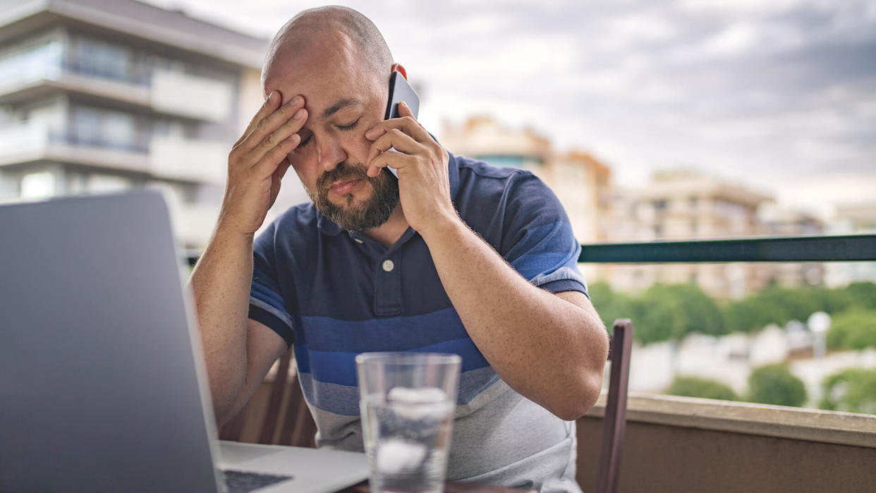 Worried and exhausted male talking on phone at balcony.