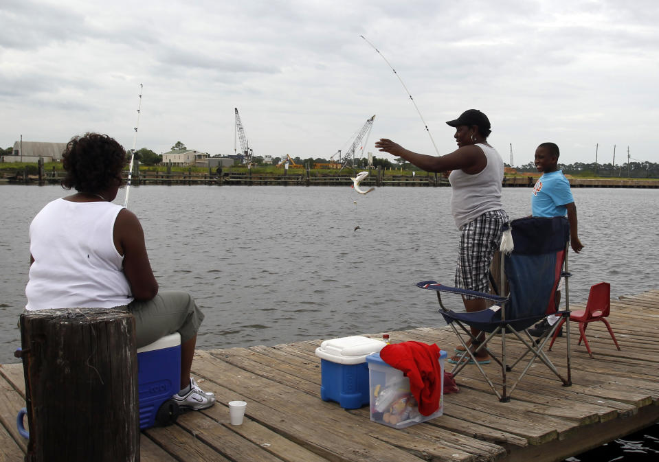 Renay Orr, left, and Taytay Harris watch as Franchy Coleman, center, reels in a Trout in Bayou La Batre, Ala. on Monday, Aug. 27, 2012. The National Hurricane Center predicted Isaac would grow to a Category 1 hurricane over the warm Gulf and possibly hit late Tuesday somewhere along a roughly 300-mile (500-kilometer) stretch from the bayous southwest of New Orleans to the Florida Panhandle. The size of the warning area and the storm's wide bands of rain and wind prompted emergency declarations in four states, and hurricane-tested residents were boarding up homes, stocking up on food and water or getting ready to evacuate. (AP Photo/Butch Dill)