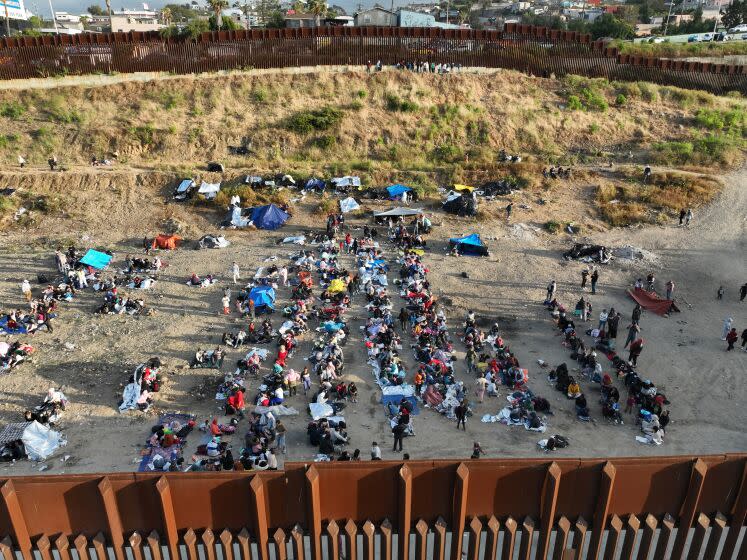 U.S. border, United States-May 11, 2023-With less than 24 hours until Title 42 expires, U.S. border patrol agents make contact with migrants hoping to cross into the United States from Tijuana, Mexico on May 11, 2023. Some migrants have been waiting a week in an area south of the second border wall in anticipation of a change in immigration policy, Title 42, which may allow them to apply for asylum. U.S. border patrol agents give out one bottle of water and one granola bar to each person. There are approximately 500 people in this one camp. (Carolyn Cole / Los Angeles Times)