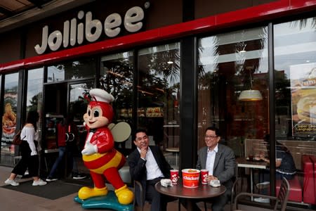 Ernesto Tanmantiong, President and CEO of Philippine national champion Jollibee Foods Corp, and CFO Ysmael Baysa, pose for a picture outside a Jollibee branch in Pasig City