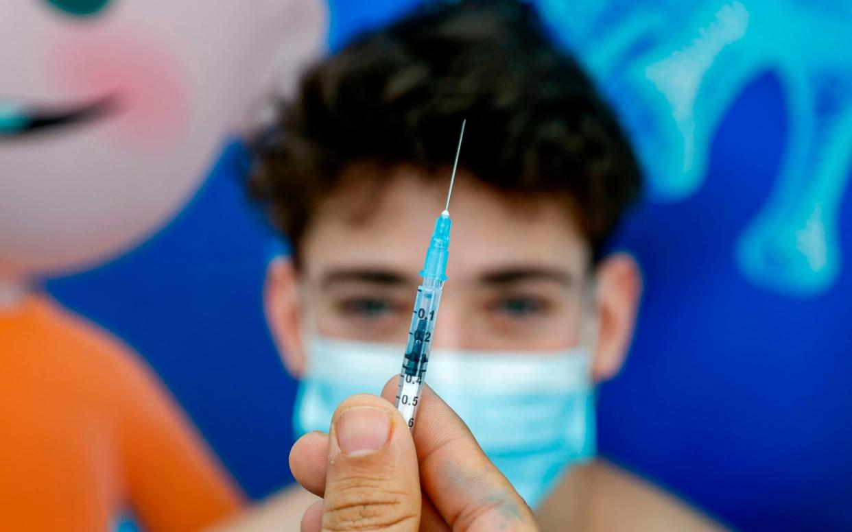 A 16-year-old teenager receives a dose of the Pfizer vaccine at Clalit Health Services, in Israel's Mediterranean coastal city of Tel Aviv  - AFP