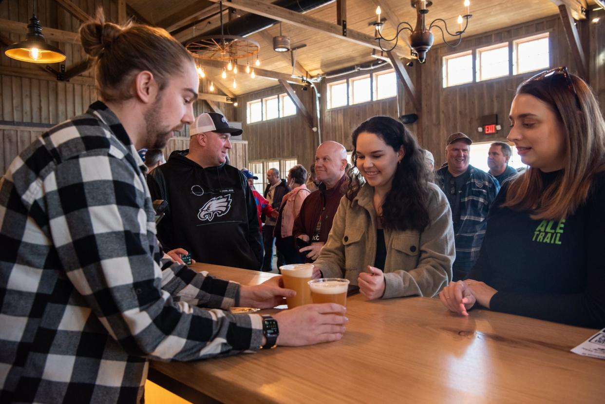 Jordan Bowser, left, tasting room manager at Warwick Farm Brewing, serves beers to Jenna Scull, center, of Yardley, and Rachel MacAyley, of Philadelphia, inside the brewery's new tasting room on Friday, February 11, 2022.