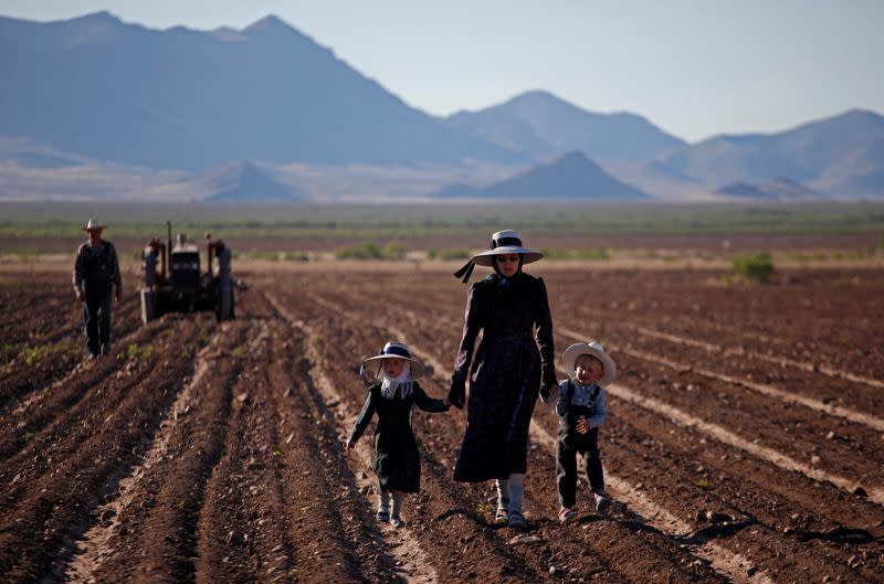 Una mujer camina con sus dos hijos por un campo agrícola en la comunidad menonita de El Sabinal, Ascensión, Chihuahua, México