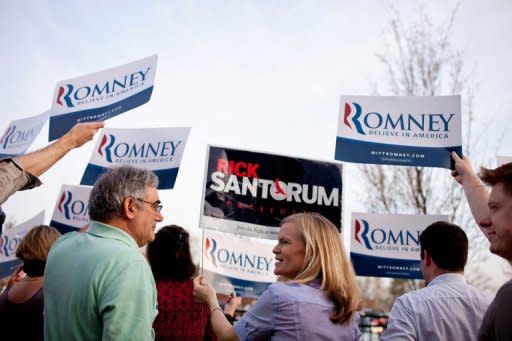 Rock Erekson (L), a Mitt Romney supporter, and Libby Wilkinson (C), a Rick Santorum supporter, display signs before Republican presidential Rick Santorum was to arrive for a campaign stop at Westminster Christian Academy, a caucus location in Town and Country, Missouri