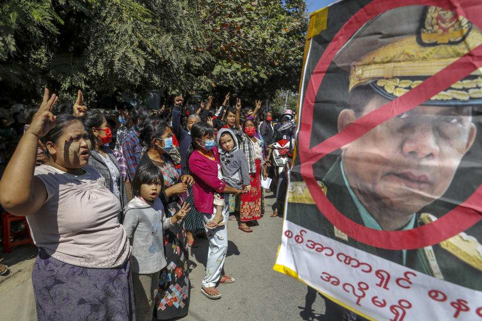 Demonstrators shout slogans and flash a three-fingered symbol of resistance against the military coup standing next to a defaced image of Myanmar military Commander-in-Chief Senior Gen. Min Aung Hlaing in Mandalay, Myanmar on Wednesday, Feb. 10, 2021. Protesters continued to gather Wednesday morning in Mandalay breaching Myanmar's new military rulers' decrees that effectively banned peaceful public protests in the country's two biggest cities. (AP Photo)