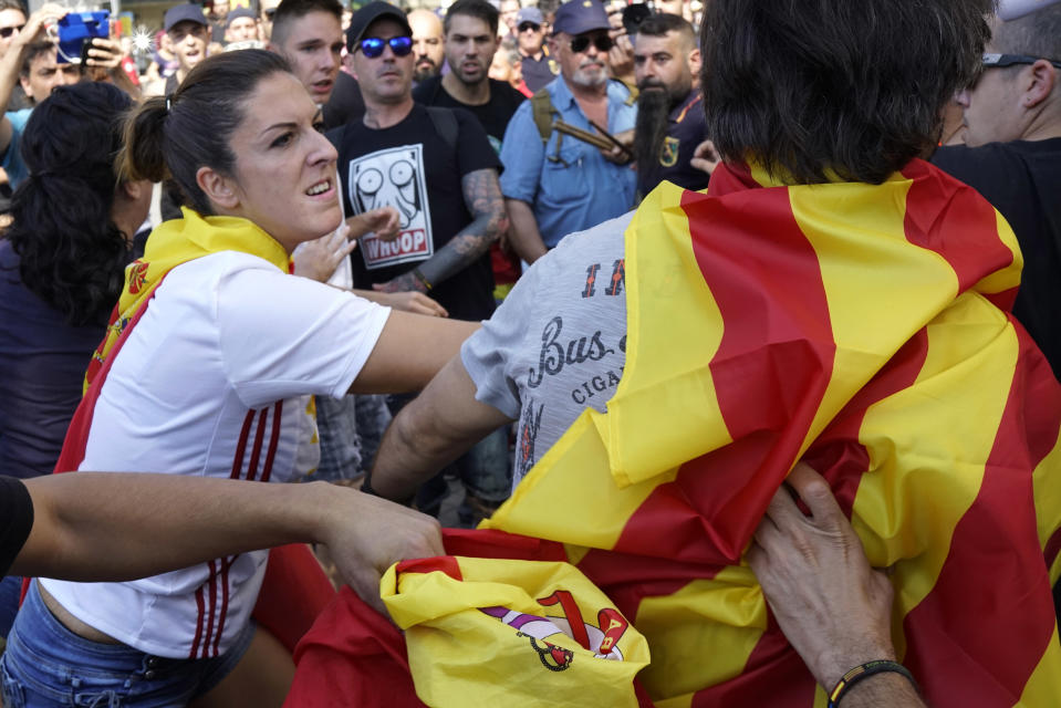 A woman wearing a Spanish flag hits a man wearing an Independence flag, followinga demonstration erupting in clashes in Barcelona, Spain, on Saturday, Sept. 29, 2018. Catalan separatists clashed with police on Saturday in downtown Barcelona as tensions increase before the anniversary of the Spanish region's illegal referendum on secession that ended in violent raids by security forces. (AP Photo/Daniel Cole)