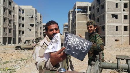 Members of the East Libyan forces shows flags of Islamist-led rivals after capturing their final holdout in the southwest of Benghazi, Libya, March 18, 2017. REUTERS/Stringer