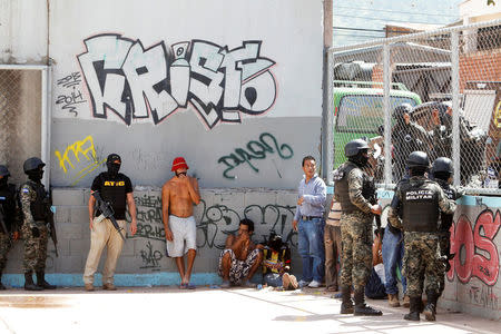 FILE PHOTO: Military policemen keep watch on suspected MS-13 gang members detained during Operation Hunter, before taking them to police facilities for an investigation on a clandestine mass grave where the gang buried their victims, according to local media, in Tegucigalpa, Honduras, June 20, 2016. REUTERS/Jorge Cabrera/File Photo