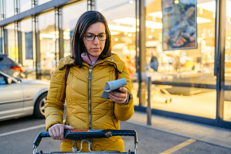 person looking down with frustration at a grocery receipt at the store