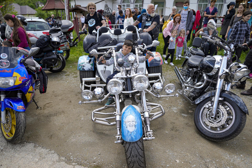 Children pose on motorcycles belonging to the members of the group Bikers for Humanity during an eyesight examination event, in Nucsoara, Romania, Saturday, May 29, 2021. Dozens of disadvantaged young Romanian children got a chance to get their eyesight examined for the first time in their lives during an event arranged by humanitarian organization Casa Buna, or Good House, which has played a prominent role in supporting the local children's lives throughout the pandemic. (AP Photo/Vadim Ghirda)