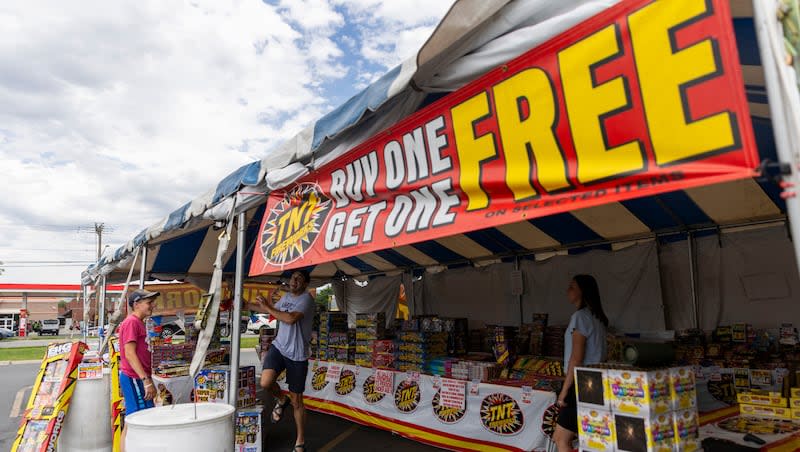 Harrison Roberts, his wife Karlie and brother Davis play with a basketball while they staff their TNT tent selling fireworks on Redwood Road in Salt Lake City on Monday. Utah's Fourth of July fireworks window runs from Tuesday through Friday.