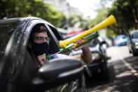 A demonstrator shouts "Out Bolsonaro" while using a noisemaker during a caravan to protest the government's handling of the COVID-19 pandemic and demand the impeachment of Brazilian President Jair Bolsonaro in Rio de Janeiro, Brazil, Saturday, Jan. 23, 2021. (AP Photo/Bruna Prado)