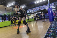 Caitlin Carroll, center, warms up before a practice , Tuesday, March 19, 2023, at United Skates of America in Seaford, N.Y. (AP Photo/Jeenah Moon)