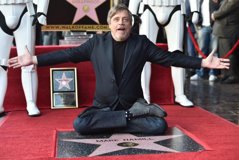 Mark sitting cross-legged  in front of his star on the Hollywood Walk of Fame with his arms stretched out and stormtroopers standing behind him