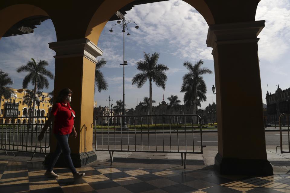 A woman, wearing a mask as a preventive measure against the spread of the new coronavirus, walks through an empty Plaza de Armas de Lima in downtown Lima, Peru, March 18, 2020. (AP Photo/Martin Mejia)