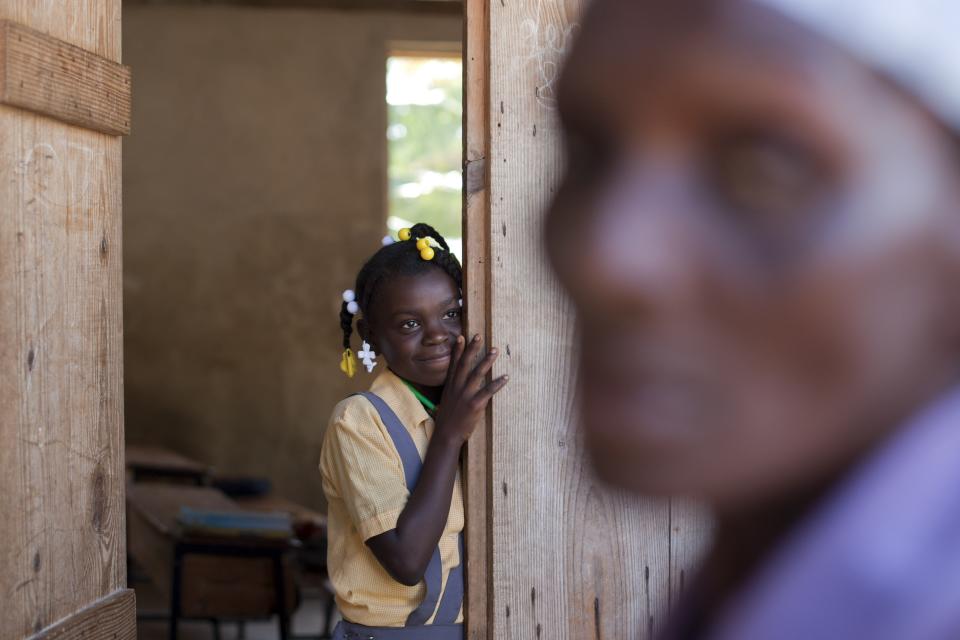 In this Tuesday, March 25, 2014 photo, Brenia Petit-Jean, 12, looks out from a classroom while her mother queues for food donated by the U.N. World Food Program, WFP, at a local school in Bombardopolis, northwestern Haiti. Drought is hitting this region, one of the hungriest, most desolate parts of the most impoverished nation in the hemisphere and it has alarmed international aid organizations such as the WFP, which sent workers this week to pass out bulgur wheat, cooking oil and salt. (AP Photo/Dieu Nalio Chery)