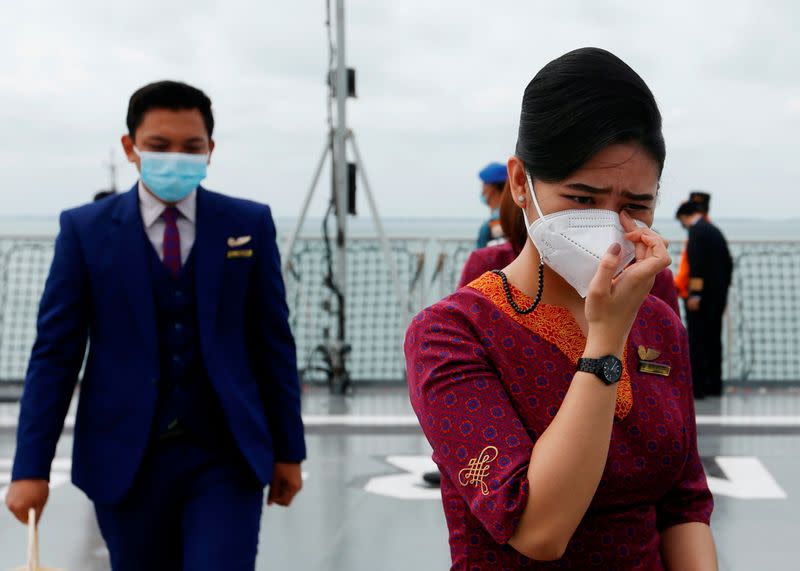 Flight attendants of Sriwijaya Air react as they visit the site of the crash of Sriwijaya Air flight SJ 182 to pay their tribute, on the deck of Indonesia's Naval ship KRI Semarang at the sea off the Jakarta coast