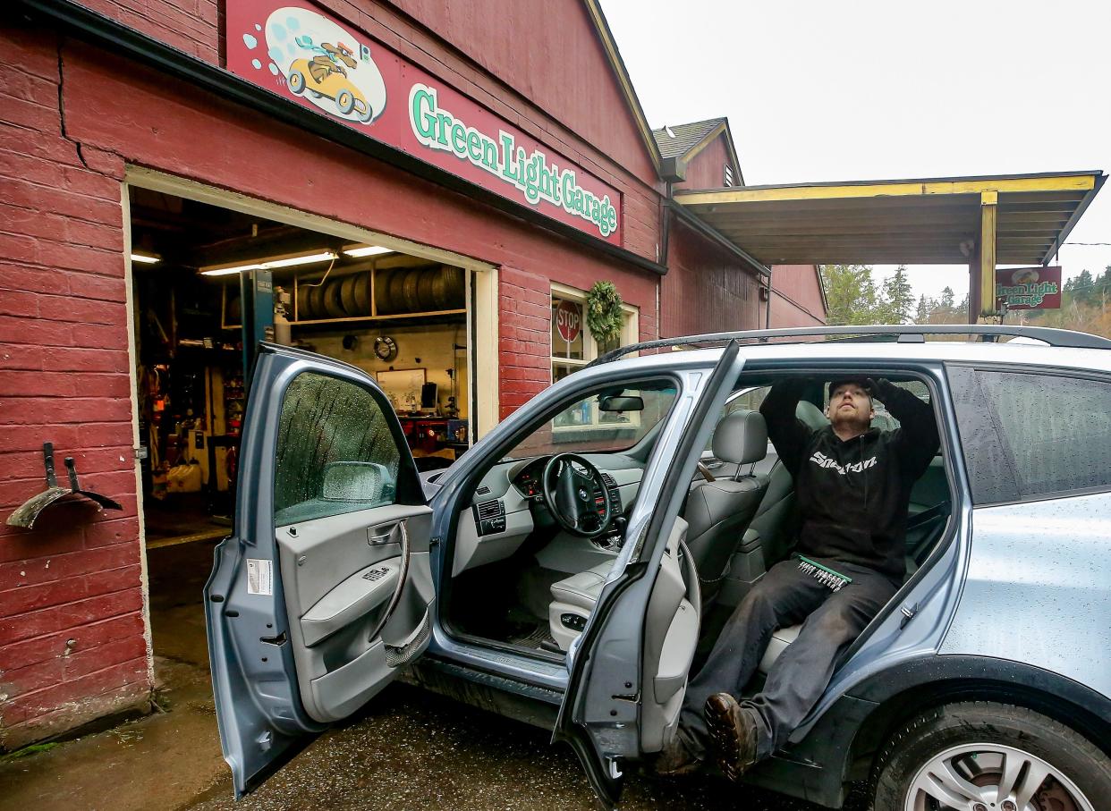 Nick Allen works on repairing the sunroof of a vehicle at his business, Green Light Garage, on Bainbridge Island on Thursday. Allen is concerned that a city plan to build a new bike lane on Eagle Harbor Drive could disrupt operations at his longtime auto shop.