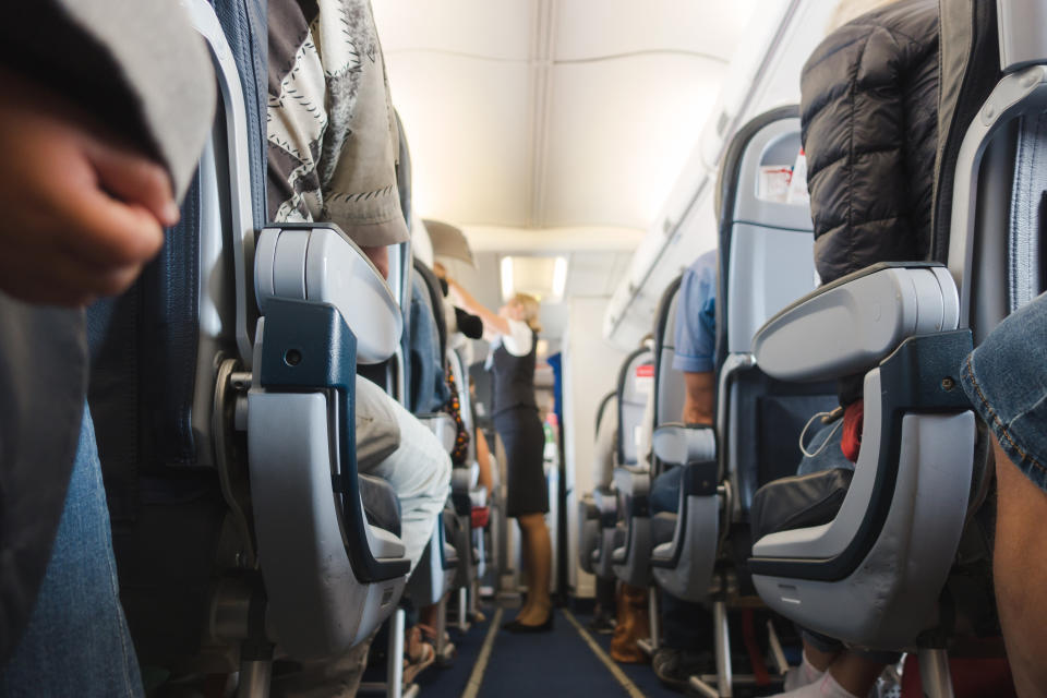 Cabin aisle in airplane with rows of seats and passengers.