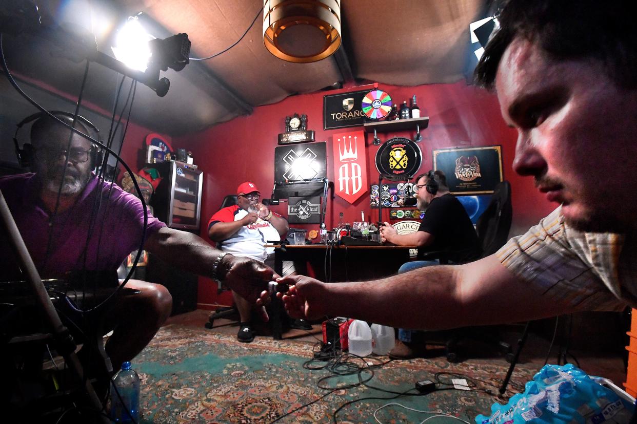 Larry Denton (left) passes a fresh cigar to Matthew Rhine as Rob Jones and Bryant Falconer continue recording an episode of their "The Cigar Talk" podcast April 3. Jones said the appeal of their show is that listeners feel like they are sitting with friends and listening to stories, all while enjoying a good cigar.