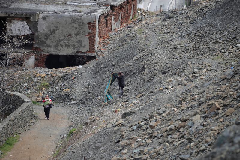 A man carrying his child walks near a mining zone in Bulqiza