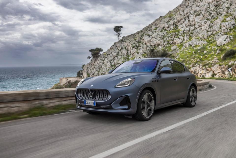 a car driving on a road by a cliff and water