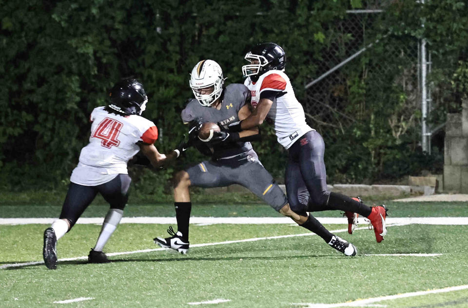 Roger Bacon wide receiver Landen Murphy (9) catches a pass between Hughes defenders Elijah Engleman andJayvion Samford (4) during their football game Friday, Sept. 1, 2023.