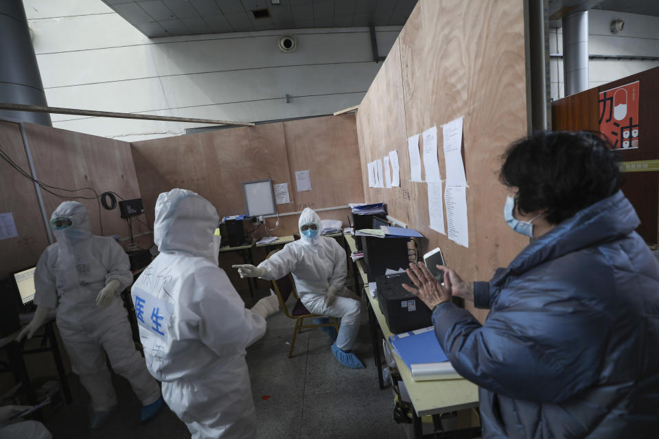 In this Friday, Feb. 21, 2020, photo, a patient consults with doctors in protective suits at a temporary hospital at Tazihu Gymnasium in Wuhan in central China's Hubei province. China's leadership sounded a cautious note Friday about the country's progress in halting the spread of the new virus that has now killed more than 2,200 people, after several days of upbeat messages. (Chinatopix via AP)