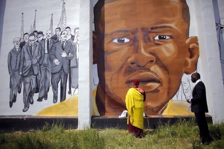 Gyalwang Drukpa (C), a Buddhist leader from South Asia, prays in front of a mural of Freddie Gray in Baltimore, Maryland, May 7, 2015. REUTERS/Carlos Barria