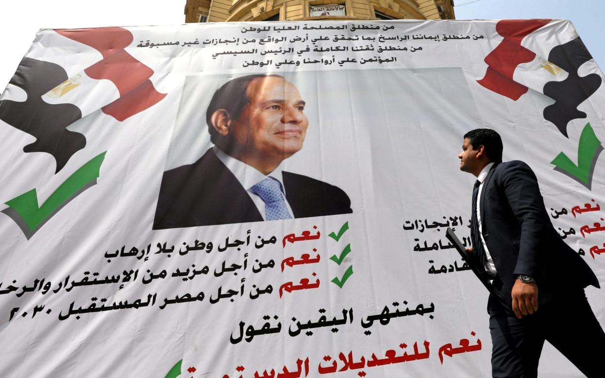 A man walks in front of a banner reading,