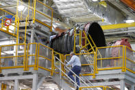 An employee walks up to two of the four rocket engines of NASA's Space Launch System (SLS) as the Artemis 1 rocket core stage is assembled at the NASA Michoud Assembly Center in New Orleans, Monday, Dec. 9, 2019. (AP Photo/Gerald Herbert)