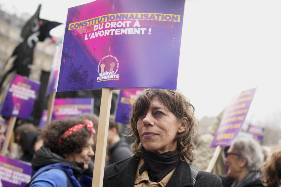 FILE - A woman demonstrates with a poster reading "Abortion in the Constitution" as part of the International Women's Day, Wednesday, March 8, 2023 in Paris. France’s National Assembly is considering a bill meant to enshrine a woman’s right to an abortion in the French Constitution. The vote scheduled for Tuesday is a key step in a legislative process that also requires a Senate’s vote. (AP Photo/Christophe Ena, File)