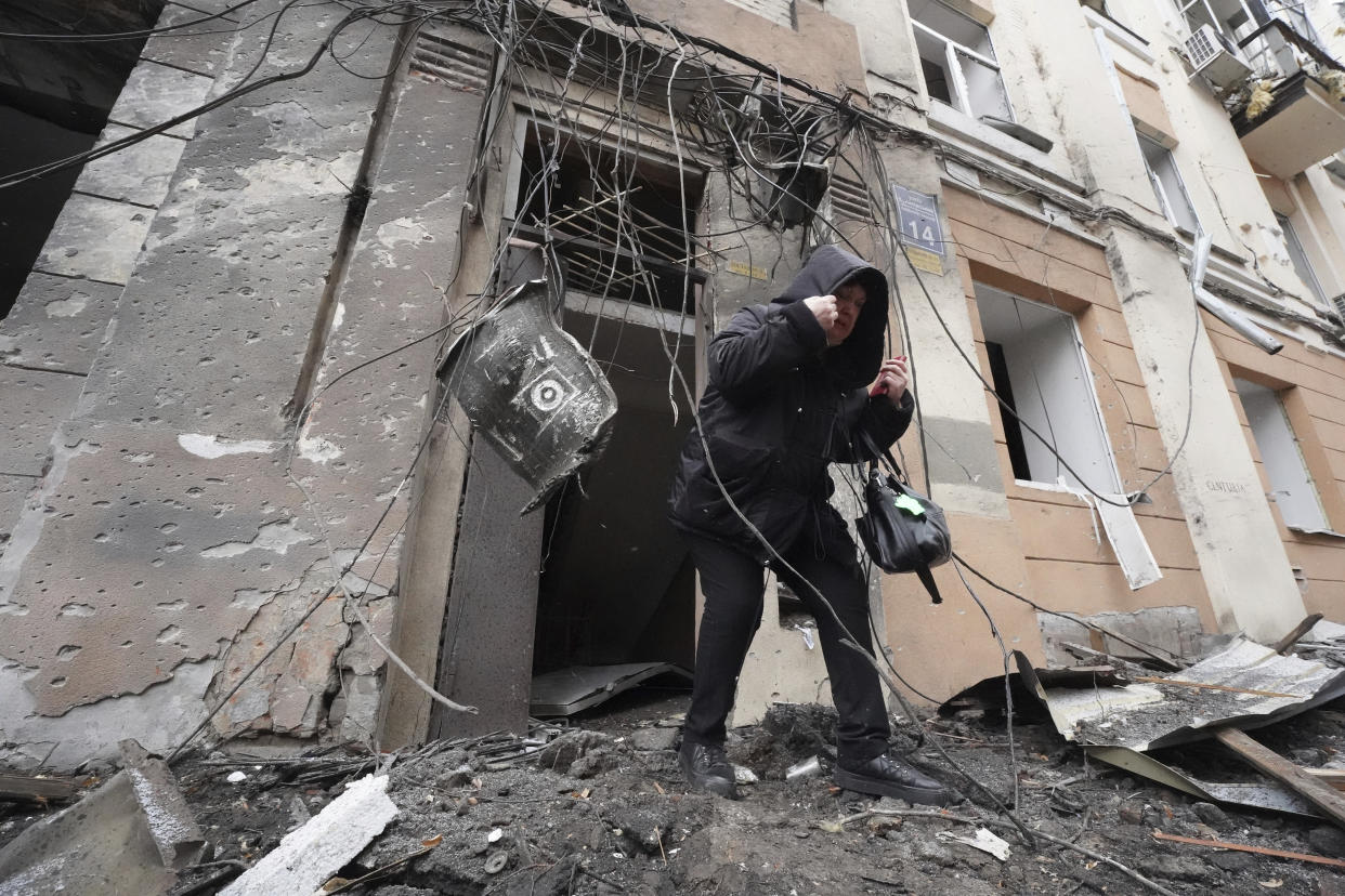 A woman walks out from a residential building which was hit by a Russian rocket, in the city center of Kharkiv, Ukraine, Sunday, Feb. 5, 2023. (AP Photo/Andrii Marienko)