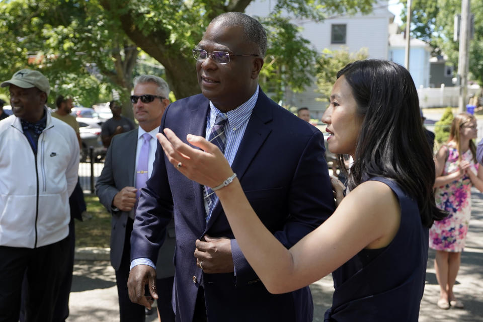 Michael Cox, center, who has been named as the next Boston police commissioner, speaks with Boston Mayor Michelle Wu, right, while greeting people as they arrives at a news conference, Wednesday, July 13, 2022, in Boston's Roxbury neighborhood. Cox, who was beaten more than 25 years ago by colleagues who mistook him for a suspect in a fatal shooting, served in multiple roles with the Boston Police Department before becoming the police chief in Ann Arbor, Michigan, in 2019. (AP Photo/Steven Senne)