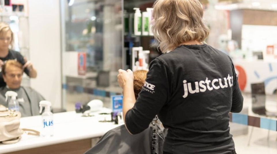 A female Just Cuts hairdressers cuts a man's hair in a Just Cuts salons in Randwick, Sydney.