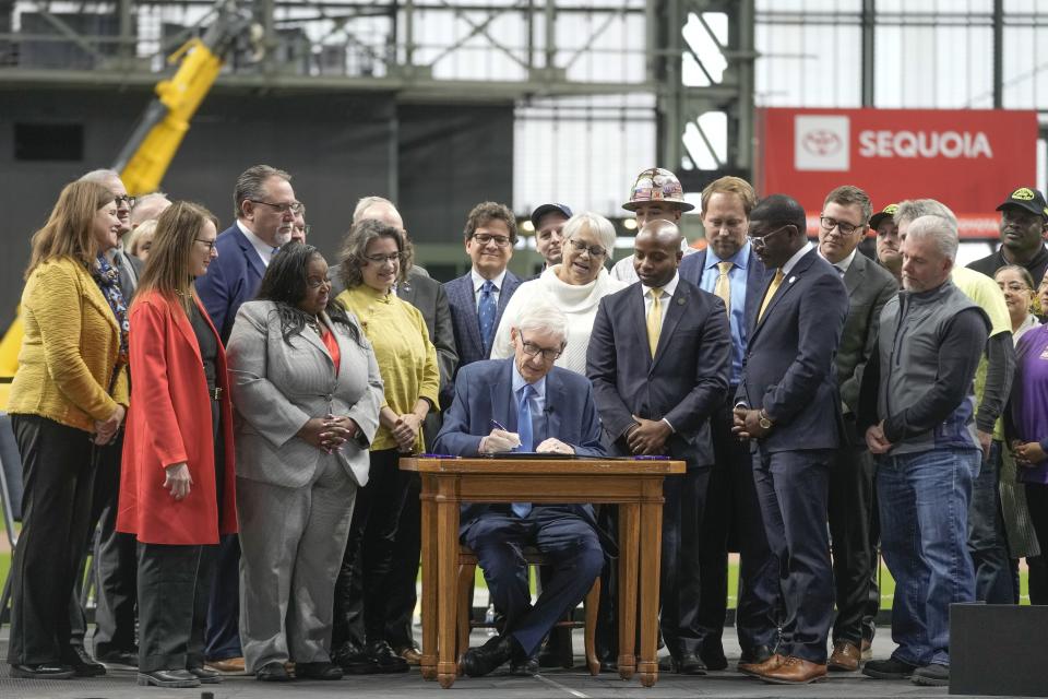 FILE - Wisconsin Gov. Tony Evers signs Assembly Bill 438 and Assembly Bill 439 at American Family Field Tuesday, Dec. 5, 2023, in Milwaukee. Proposals for new and improved sports stadiums are proliferating across the U.S. — and could come with a hefty price tag for taxpayers. (AP Photo/Morry Gash)