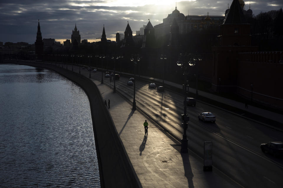 In this April 10, 2020, photo, a man rides a bike along the embankment of the Moskva River in front of the Kremlin in Moscow, Russia. As countries across the world seek to get their economies back on track after coronavirus lockdowns are over, some people are encouraging the use of bicycles as a way to avoid unsafe crowding on trains and buses. (AP Photo/Pavel Golovkin)