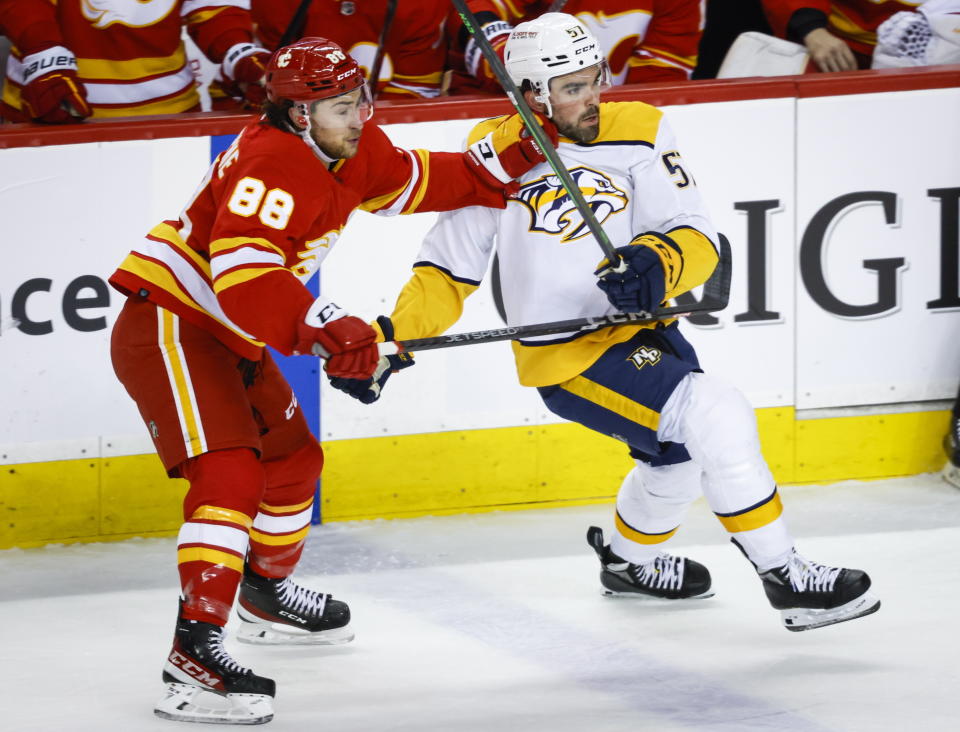 Nashville Predators defenseman Dante Fabbro, right, is checked by Calgary Flames forward Andrew Mangiapane during the first period of an NHL hockey game in Calgary, Alberta, Monday, April 10, 2023. (Jeff McIntosh/The Canadian Press via AP)