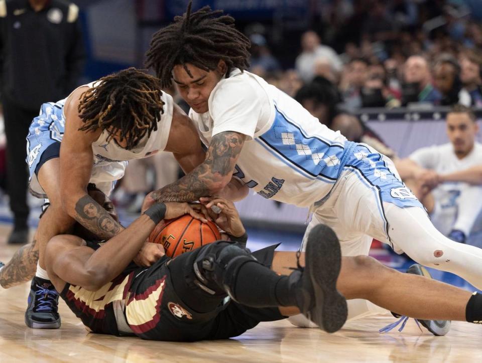 North Carolina’s R.J. Davis (4) and Elliot Cadeau (2) battle for a loose ball with Florida State’s Jaylan Gainey (33) in the first half in the quarterfinals of the ACC Men’s Basketball Tournament at Capitol One Arena on Wednesday, March 13, 2024 in Washington, D.C. Robert Willett/rwillett@newsobserver.com