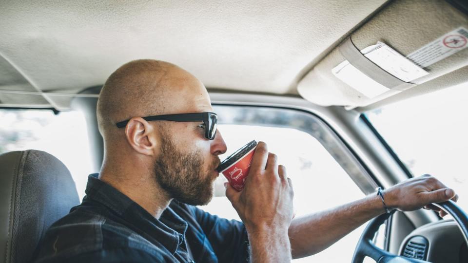 daylight saving sleep - YYoung man with sunglasses and beard on a road trip with takeaway drink