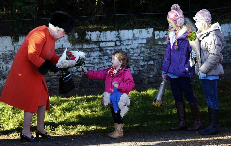 Britain's Queen Elizabeth receives flowers from children as she leaves a Christmas Day morning service at the church on the Sandringham Estate in Norfolk, eastern England, December 25, 2013. REUTERS/Andrew Winning (BRITAIN - Tags: ROYALS RELIGION)