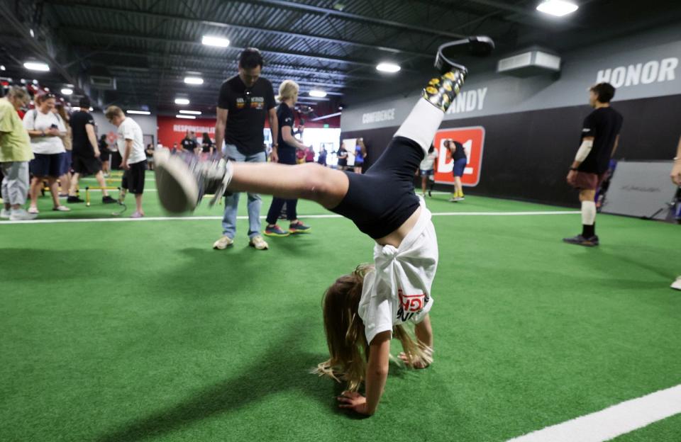 Kallie Nimer does a cartwheel after getting a new recreational prosthetic on Saturday as part of their Running is a Right program.