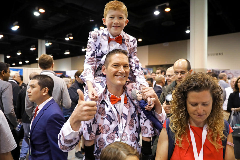 Ray Renk sostiene a su hijo Benjamin, de 10 años, mientras visten trajes hechos a medida a juego impresos con una caricatura del presidente ejecutivo de Berkshire Hathaway, Warren Buffett, en la reunión anual de accionistas en Omaha, Nebraska, EE. UU., el 4 de mayo de 2019. REUTERS/Scott morgan