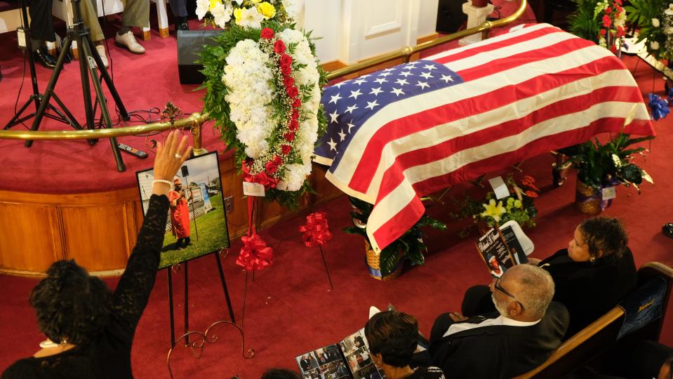 A lady raises her hands during a song at Richard Stewart's funeral.