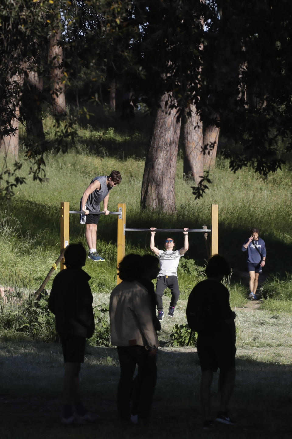 People work out on outdoor gym equipment inside Rome's Villa Pamphili park as it reopened after several weeks of closure, part of nationwide limited easing of some lockdown restrictions, on Monday, May 4, 2020. Italy began stirring again Monday after a two-month coronavirus shutdown, with 4.4 million Italians able to return to work and restrictions on movement eased in the first European country to lock down in a bid to stem COVID-19 infections. (AP Photo/Alessandra Tarantino)