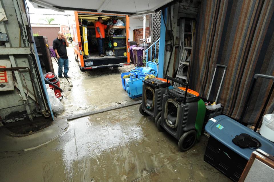 Cleanup crews work after sand and silt flooded a home and garage near Ocean Boulevard between 66th and 72nd Place, along the Peninsula in Long Beach, Calif., Sunday, March 2, 2014. Flooding occurred when heavy surf eroded the protective sand berm Saturday night, resulting in 20 homes on Ocean Blvd between 66th and 72nd Place, sustaining damage to either living levels or parking areas. No residents were reported to be displaced, said Long Beach Fire Department Public information Officer Will Nash. (AP Photo/Daily Breeze, Stephen Carr)