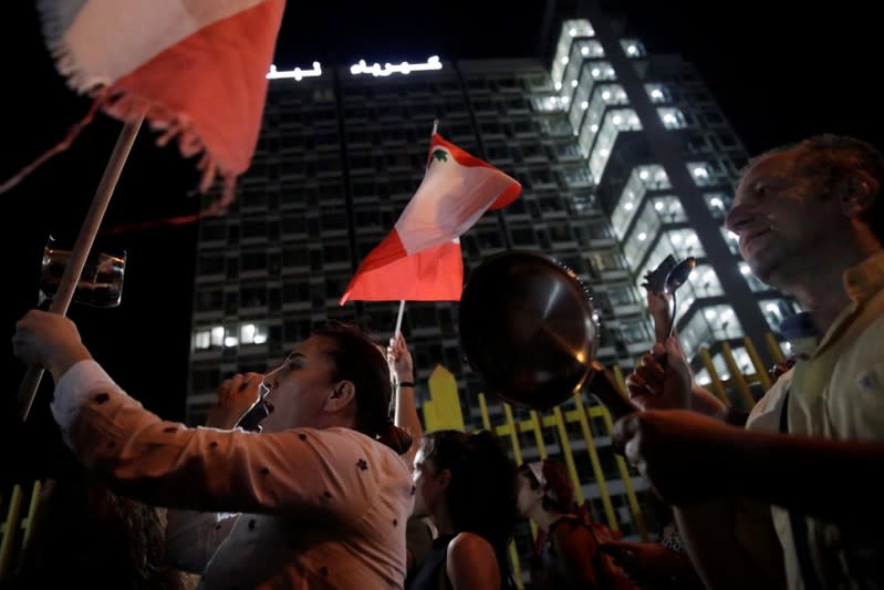 People hit pans during a protest outside of the state owned electricity company during ongoing anti-government demonstrations in Beirut