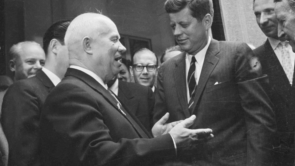 soviet premier nikita khrushchev and president john f kennedy look at each other while talking in a crowd of men