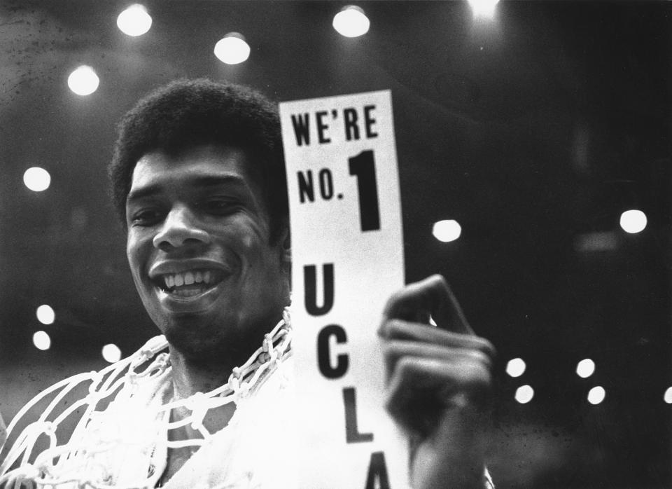 FILE - With the basket netting draped over his shoulders, Lew Alcindor, later known as Kareem Abdul-Jabbar, holds a sign after leading UCLA to a 78-55 win over North Carolina to win the NCAA college basketball championship in Los Angeles, March 23, 1968. (AP Photo/File)